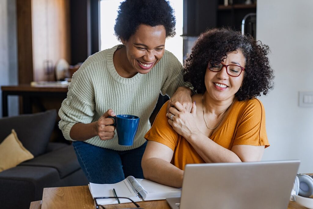 A couple looking at the computer together and smiling.
