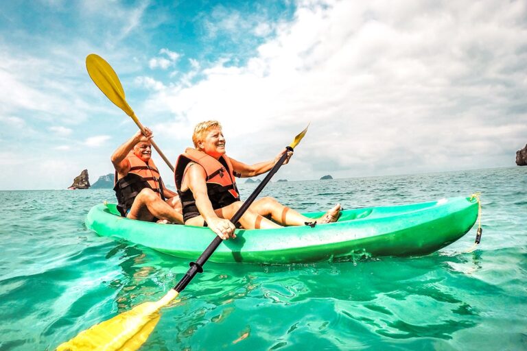 An older couple paddling in an ocean kayak.